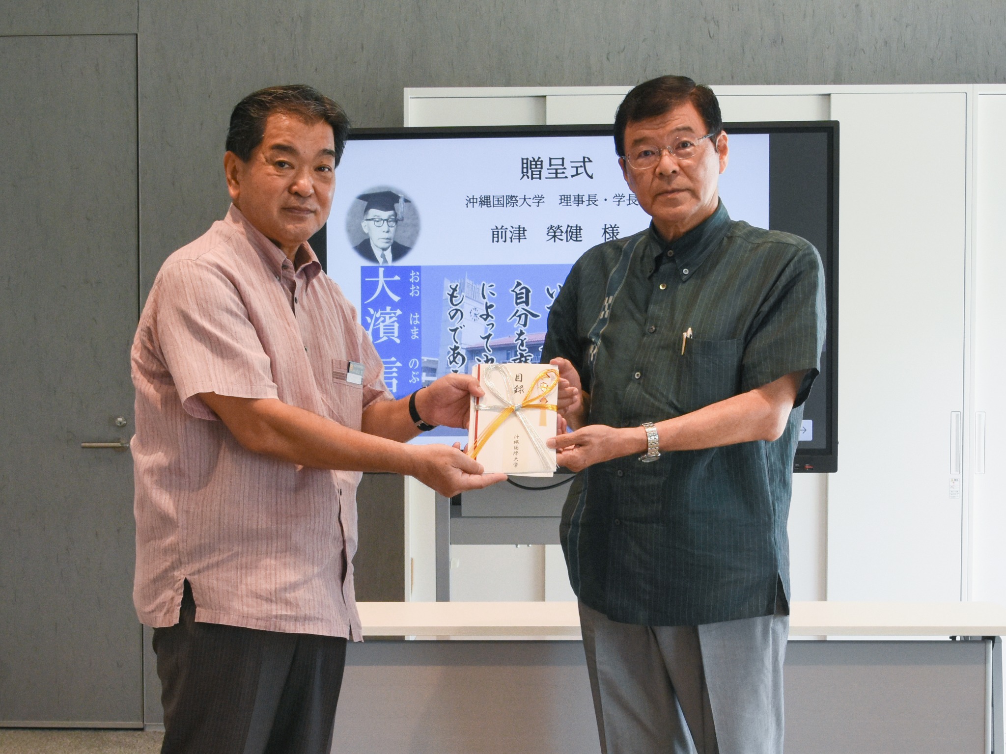 贈呈式で目録を授与する前津学長(写真右)と﨑山教育長(写真左)