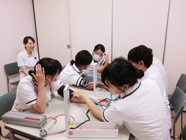 指導者から指導のもと、学生同士で血圧測定の練習をしている様子